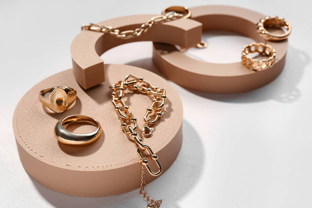 Díszítő dobogók arany gyűrűkkel és karkötőkkel fehér alapon - Fotó, kép
