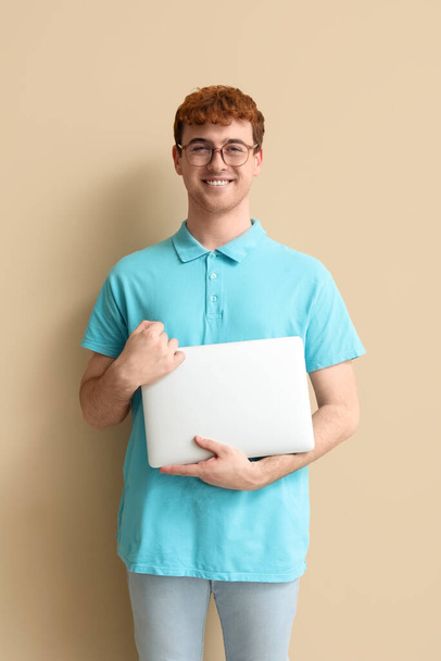 Male programmer with laptop on beige background - 写真・画像