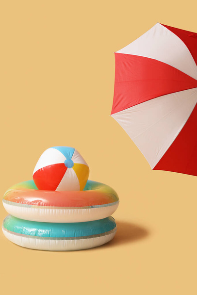 Swim rings with beach ball and umbrella on beige background - Photo, Image