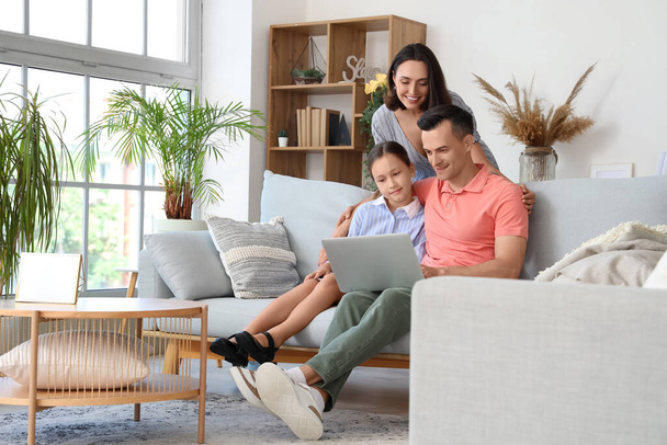 Ευτυχισμένη οικογένεια με φορητό υπολογιστή που αναπαύεται στο σαλόνι - Φωτογραφία, εικόνα