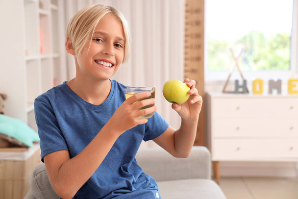 Niño pequeño con un vaso de jugo de manzana en casa - Foto, Imagen