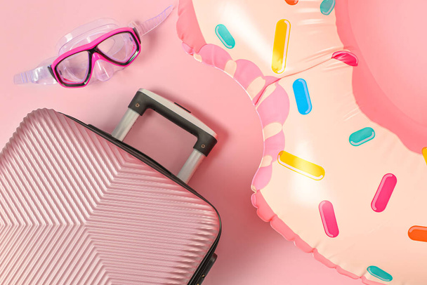 Κομψή βαλίτσα, μάσκα ψαροντούφεκο και φουσκωτό δαχτυλίδι στο φόντο χρώμα, closeup - Φωτογραφία, εικόνα