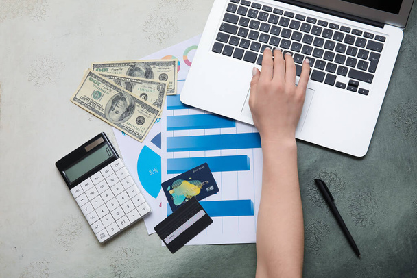 Mano femenina con tarjetas de crédito, gráficos, laptop y calculadora sobre fondo grunge gris. Casa concepto de alquiler - Foto, imagen