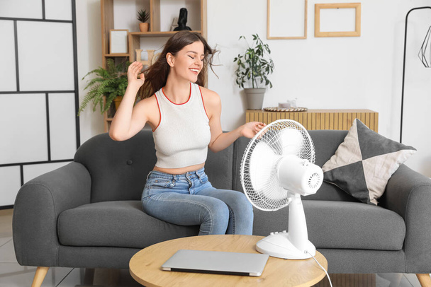 Young woman with blowing electric fan at home - Photo, Image