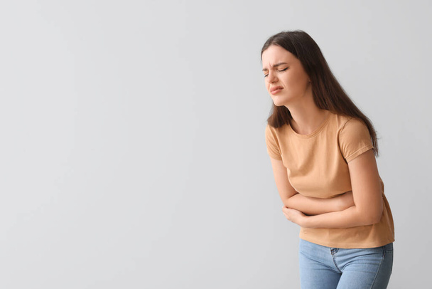 Mladá žena trpí bolestí břicha na světlém pozadí - Fotografie, Obrázek