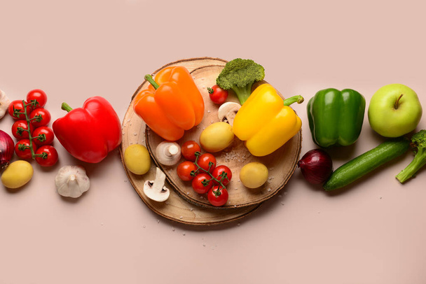 Деревянные доски с различными свежими овощами на бежевом фоне - Фото, изображение