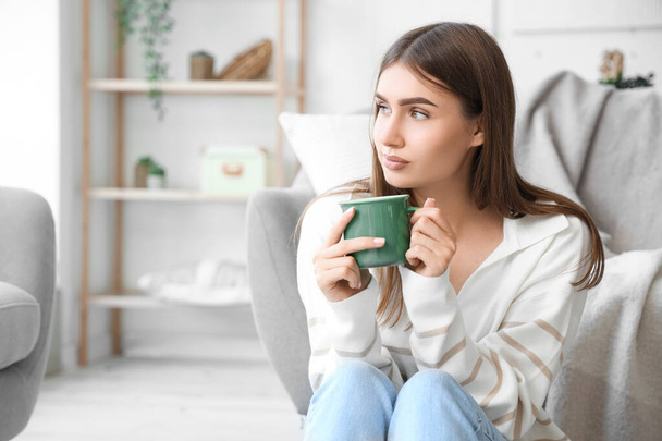 Nuori nainen kupin kuumaa teetä kotona - Valokuva, kuva