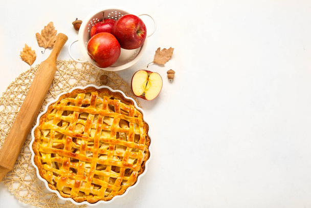 Plato para hornear con delicioso pastel de manzana e ingredientes sobre fondo blanco - Foto, Imagen