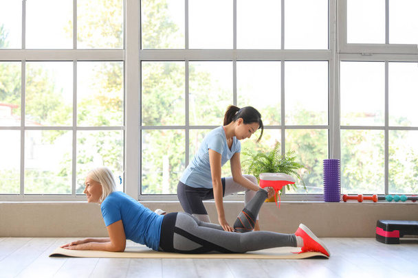 Volwassen vrouw training met therapeut op mat in revalidatiecentrum - Foto, afbeelding