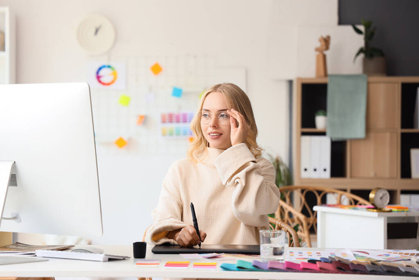 Женщина-дизайнер интерьеров работает с графическим планшетом за столом в офисе - Фото, изображение