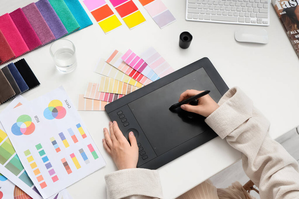 Женщина дизайнер интерьера работает с графическим планшетом за столом в офисе, вид сверху - Фото, изображение