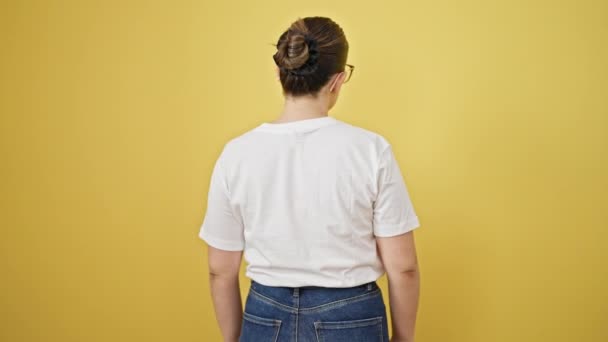 Young beautiful hispanic woman turning around smiling confident over isolated yellow background - Footage, Video