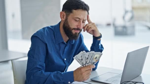 Fiatal spanyol férfi üzletember használja laptop számláló dollárt az irodában - Felvétel, videó