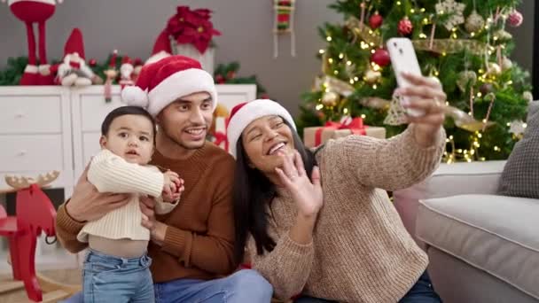 Pareja e hijo teniendo videollamada sentados en el suelo por árbol de Navidad en casa - Imágenes, Vídeo