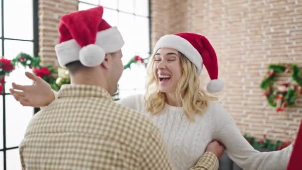 Erkek ve kadın çift birbirlerine sürpriz yaparak evde Noel hediyesiyle sarılıyorlar. - Video, Çekim