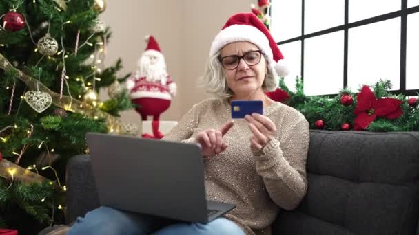 Gri saçlı orta yaşlı bir kadın evde dizüstü bilgisayarla Noel alışverişi yapıyor. - Video, Çekim