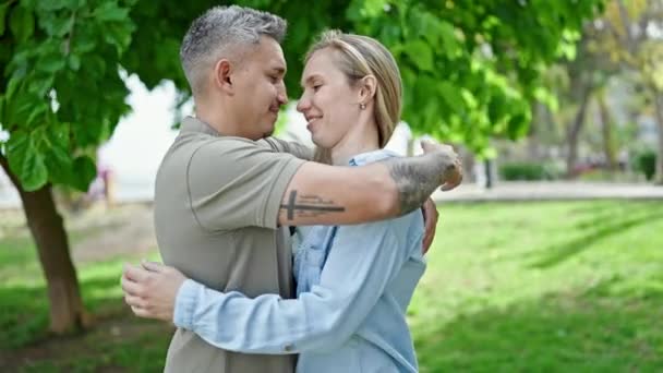 Hombre y mujer pareja abrazándose mutuamente besándose en el parque - Metraje, vídeo