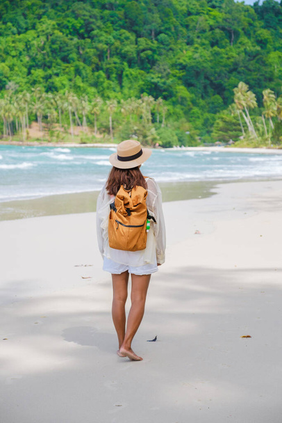 Азиатская женщина с рюкзаком гуляет на пляже Ко Куд (Koh Kood Island Thailand Trat), путешественник гуляет по пляжу тропического острова Ко Кут (Ko Kut Island) с кокосовыми пальмами на пляже, беспилотник - Фото, изображение