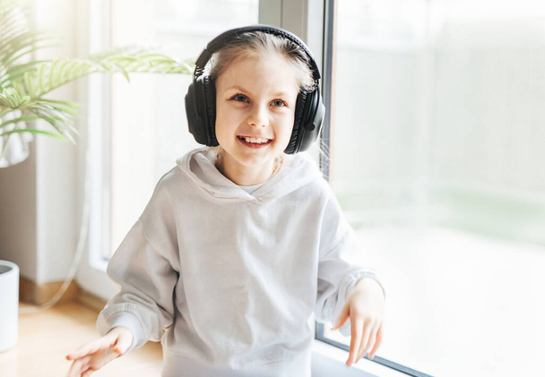 Linda niña escuchando música en auriculares en casa. - Foto, imagen