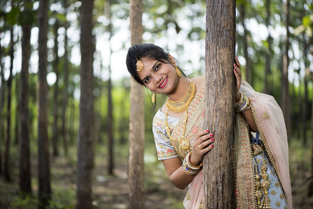 Portret van een prachtige bruid in traditionele kleding buiten in de natuur. - Foto, afbeelding