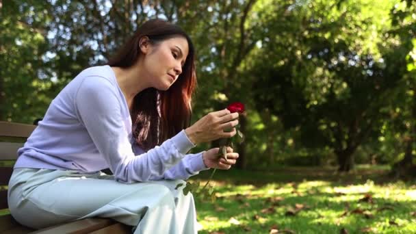 Nuori aasialainen nainen pettynyt rakkauteen istuu yksin puutarhassa poimien ruusuja ja heittää ne maahan tuskallisessa masennuksessa masentunut henki Introvert: särkynyt sydän, hajottaa, avioero Concept. - Materiaali, video