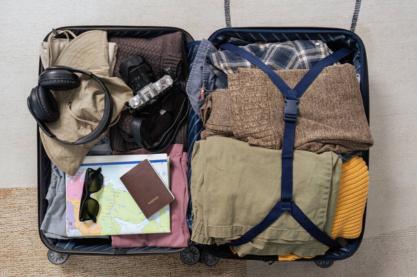 Csomagoló táska kamerával, laptoppal, hordozható akkumulátor töltővel és elektromos fogkefével. Modern utazási blogger koncepció. - Fotó, kép