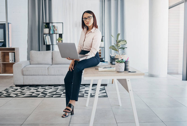 Portrait, woman and office with laptop, working and thinking in corporate clothes, alone and serious. Sitting on desk, virtual meeting and writing report for client review and business manager stats. - Photo, Image