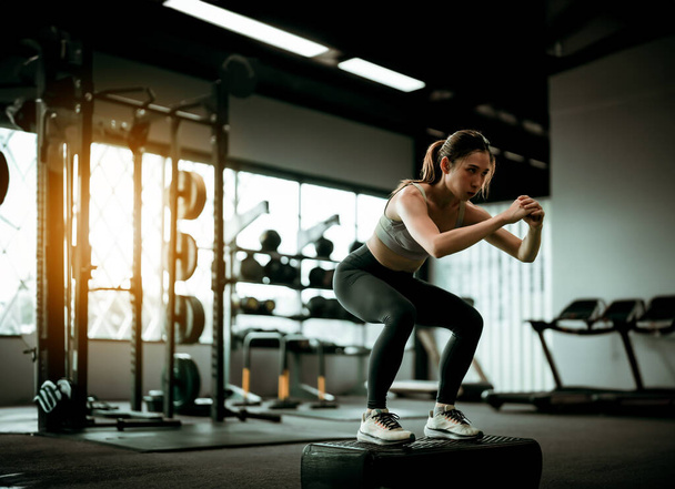 Jonge sportieve vrouw workout Oefening met Jumping Step Platform bij Fitness Center of Gym. Fitness en Wellness Concept - Foto, afbeelding