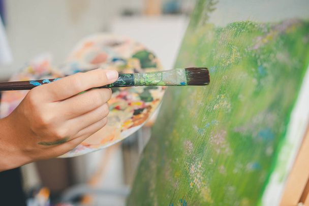 スタジオワークショップでいくつかのアートプロジェクトを行うキャンバスに水彩画塗装ブラシを用いたクローズアップアート学生の手 - 写真・画像