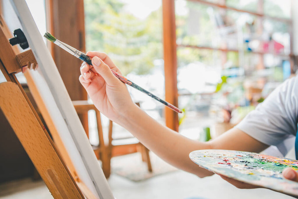 közeli művészeti hallgató kezét akvarell ecset festés vásznon csinál néhány művészeti projektek stúdió műhely - Fotó, kép