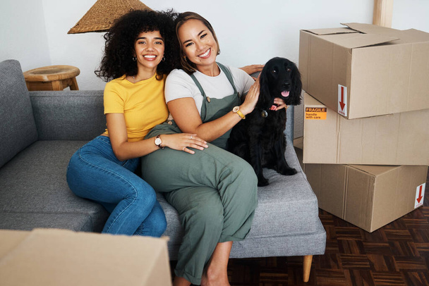 Homeowner, portrait and lesbian couple with a dog on the sofa for moving boxes and a new home. Smile, lgbt and women or people on the living room couch of an apartment with a pet after relocation. - Photo, Image