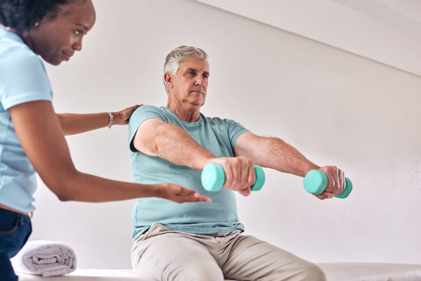 Physiotherapy, exercise and old man with dumbbell for wellness and muscle training on bed with woman in room. Healthcare, physiotherapist and senior with workout for healing help, support and fitness. - Photo, Image
