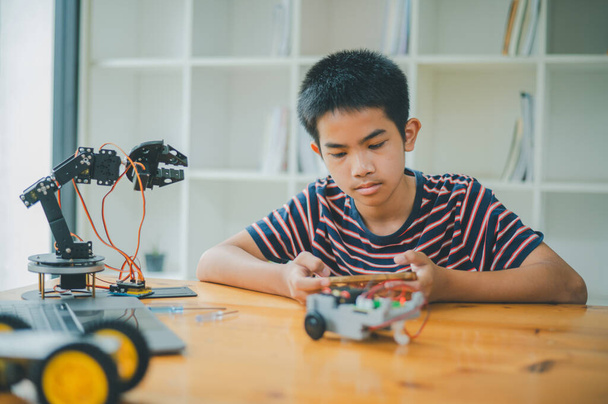 Asyalı çocuk teknoloji robotlarının çalışmalarını öğreniyor ve inceliyor. Teknoloji projesi için ev okulu ve bilim. Çocukluk çocukları hobisi eğlence yaşam tarzı oyuncakları robot teknolojisi. - Fotoğraf, Görsel