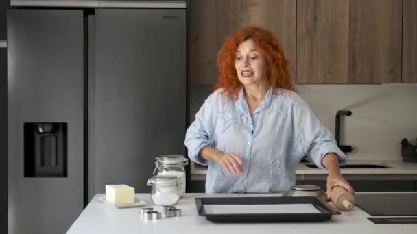 Kaukasische roodharige vrouw legt boter koekjes recept met gebarentaal. - Video