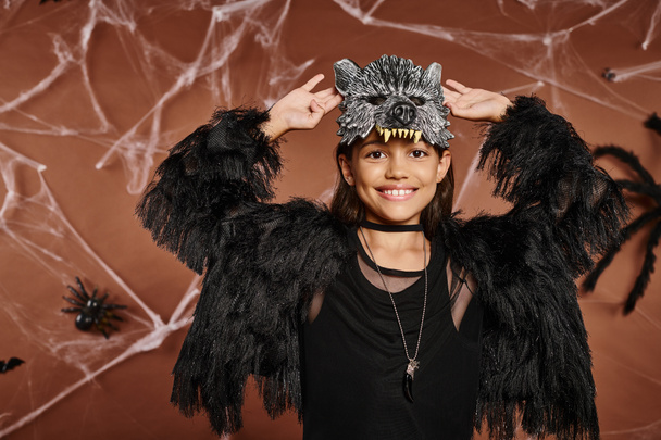 zbliżenie uśmiechnięty nastolatek dziewczyna z podniesionymi rękami w czarny faux futro strój, koncepcja Halloween - Zdjęcie, obraz