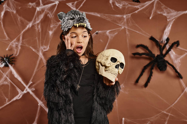 close up terrified preteen girl wearing wolf mask holds skull in her hands, Halloween concept - Photo, Image