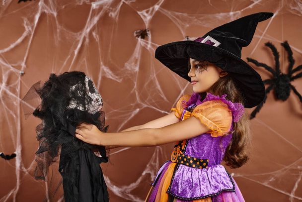 Закрыть ребенка-подростка с жуткой игрушкой и глядя на нее, коричневый фон, Хэллоуин концепции - Фото, изображение