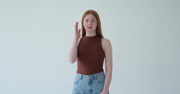 Una ragazza adolescente è raffigurata fare un gesto facepalm su uno sfondo bianco. Con la mano appoggiata sulla fronte per frustrazione o incredulità, la sua espressione trasmette esasperazione o delusione. - Filmati, video