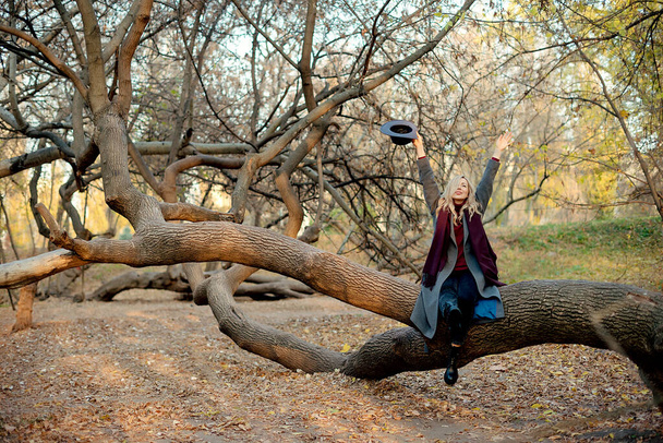 Piękna szczęśliwa kobieta relaksująca się w jesiennym parku. Równowaga i harmonia z naturą - Zdjęcie, obraz
