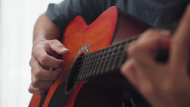 Detailní záběr muže ruce hrát na akustickou kytaru sedí na pohovce v obývacím pokoji doma. - Záběry, video