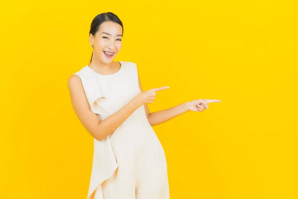 Portrait belle jeune femme asiatique sourire avec action sur fond de couleur jaune - Photo, image