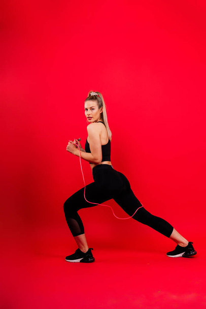 Fitness-Frau macht Sprungübungen mit Springseil auf buntem gelben Hintergrund. - Foto, Bild