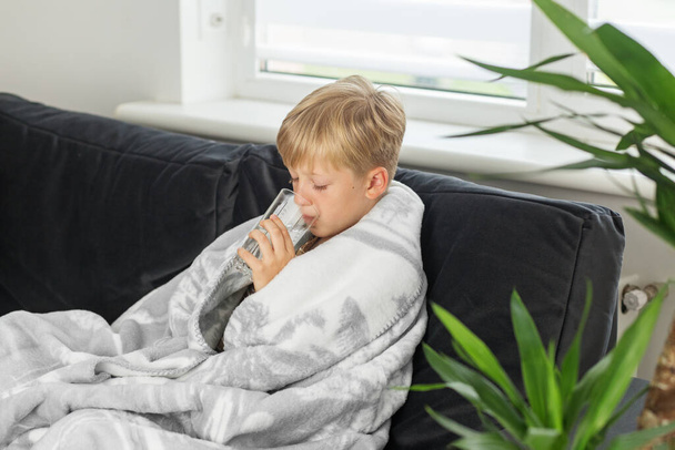 Kranker preteen Junge mit hohem Fieber und Halsschmerzen und einem schlechten Gefühl, zu Hause auf dem Sofa sitzend - Foto, Bild