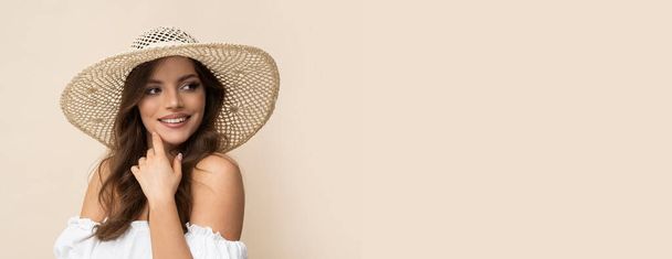 Mujer joven muy hermosa en sombrero de paja y vestido boho blanco sobre fondo cremoso. - Foto, Imagen