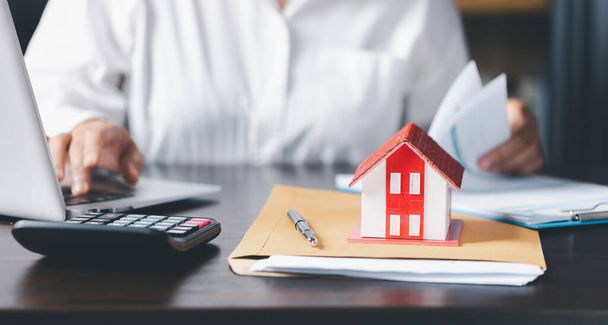 Model domu z agentem nieruchomości i klientem dyskutującym o umowie kupna domu, ubezpieczenia lub kredytu tła nieruchomości. oszczędności monet stos przyszłość dla domu - Zdjęcie, obraz