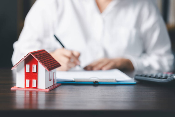 Model domu z agentem nieruchomości i klientem dyskutującym o umowie kupna domu, ubezpieczenia lub kredytu tła nieruchomości. oszczędności monet stos przyszłość dla domu - Zdjęcie, obraz