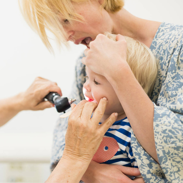Menino bebê criança sendo examinado por seu médico pediatra durante um check-up médico padrão na presença e conforto de sua mãe. Saúde pública nacional e cuidados infantis koncept - Foto, Imagem