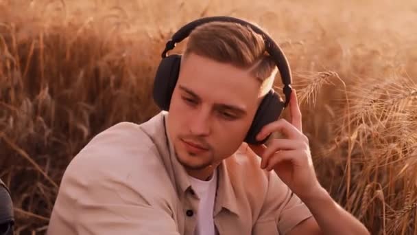 adolescent guy dans casque écouter de la musique, couché sur l'herbe, heureux été - Séquence, vidéo