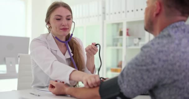 Arts met behulp van shygmomanometer met stethoscoop controleert de bloeddruk van de patiënt in het ziekenhuis. Gezondheidszorg en medisch onderzoek - Video