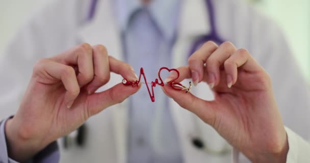 Ο γιατρός κρατάει στα χέρια του ένα εικονίδιο με καρδιογράφημα καρδιάς. Έννοια της καρδιοαγγειακής νόσου - Πλάνα, βίντεο
